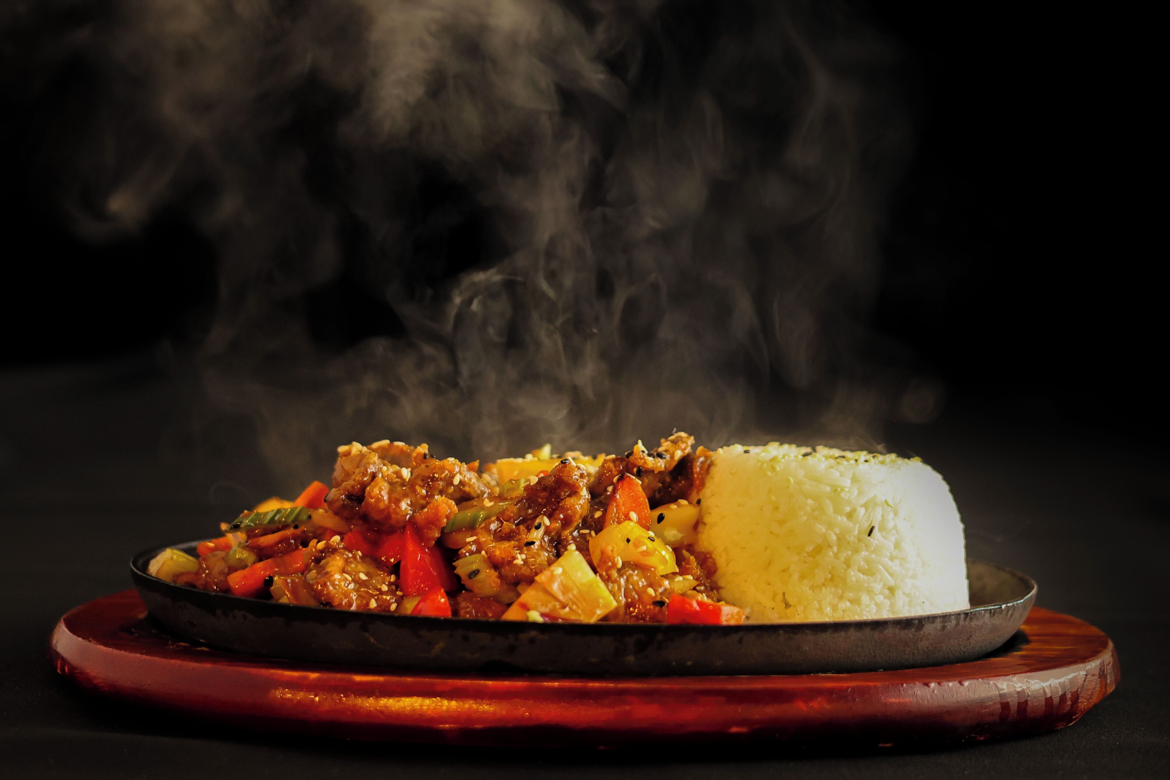 Un piatto di cibo con riso e carne, dal quale sale il vapore.