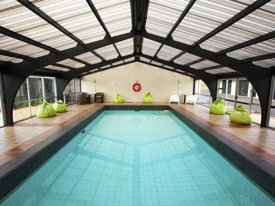 Ein überdachter Schwimmbereich mit hoher Decke und Fliesenboden.
