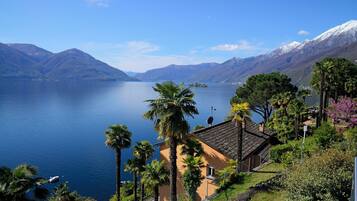 A coastal property with a view of a calm lake, surrounded by mountains and palm trees.