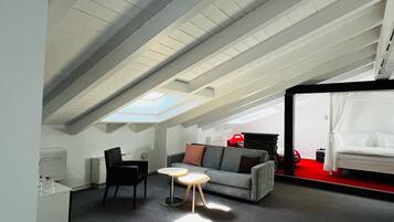 Une chambre mansardée chaleureuse, avec un puits de lumière, un lit, un canapé et une petite table.