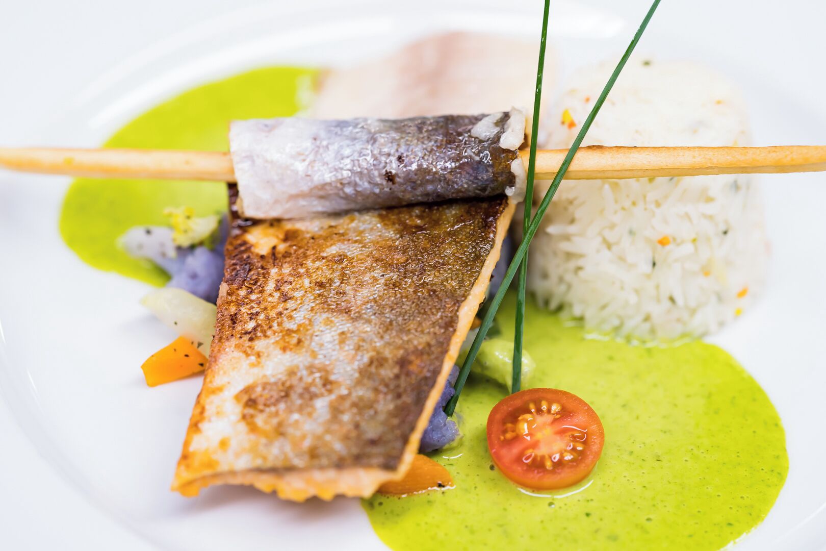 A plate with grilled fish, rice, and a green sauce.