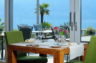 Una mesa de comedor dispuesta con cristalería, una carta y un florero con flores.