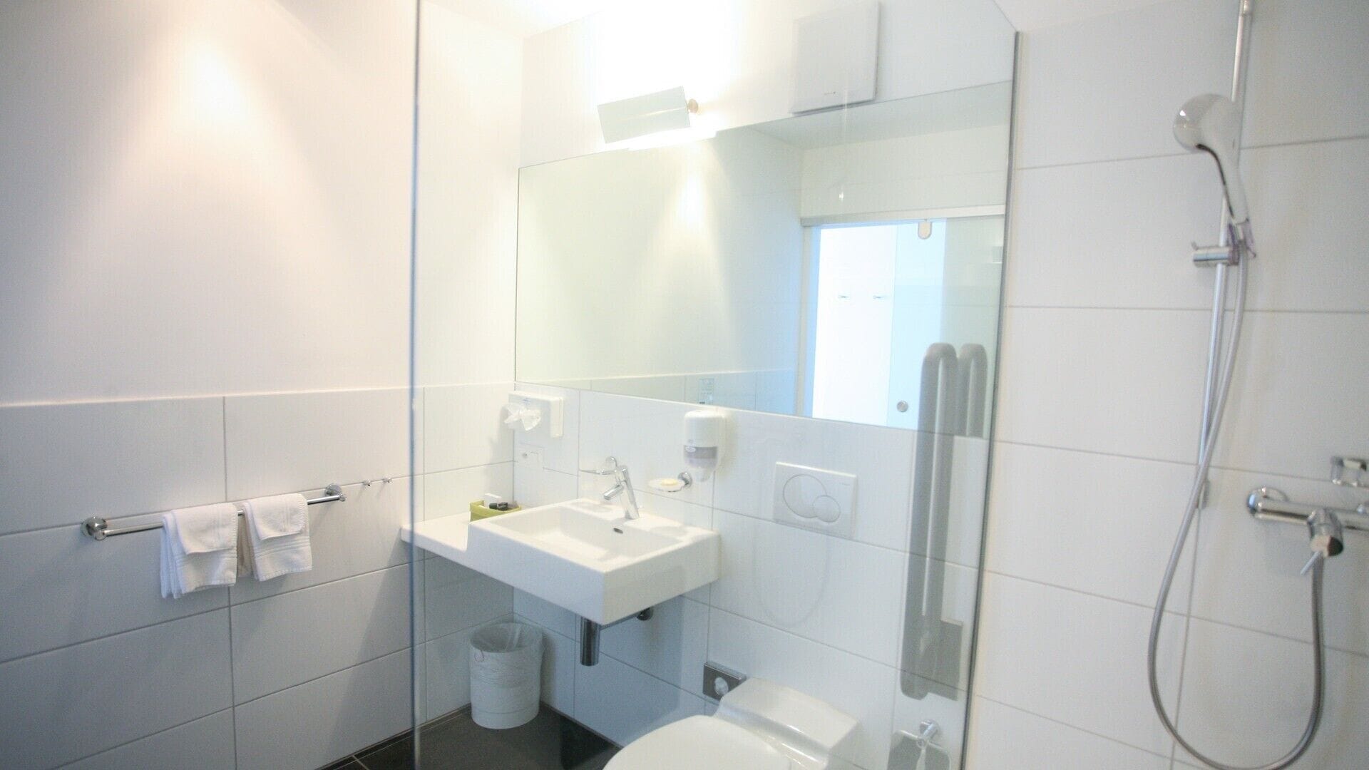 A modern bathroom with a glass partition, a sink, a toilet, and a shower.