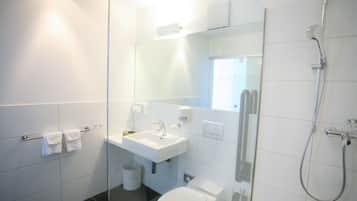 Un baño moderno con mampara de vidrio, lavamanos, inodoro y ducha.