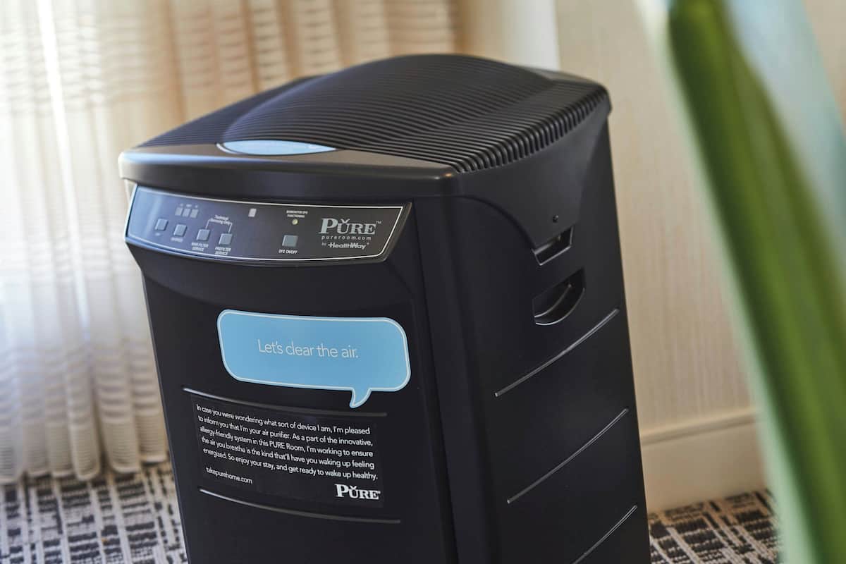 A black air purifier with a digital display and a blue speech bubble saying "Let's clear the air."