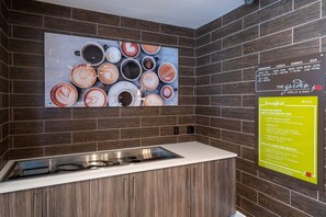 A kitchen area with a stainless steel sink and a wall-mounted menu board listing breakfast options. - Hilton Garden Inn Temple Medical Center (Temple)