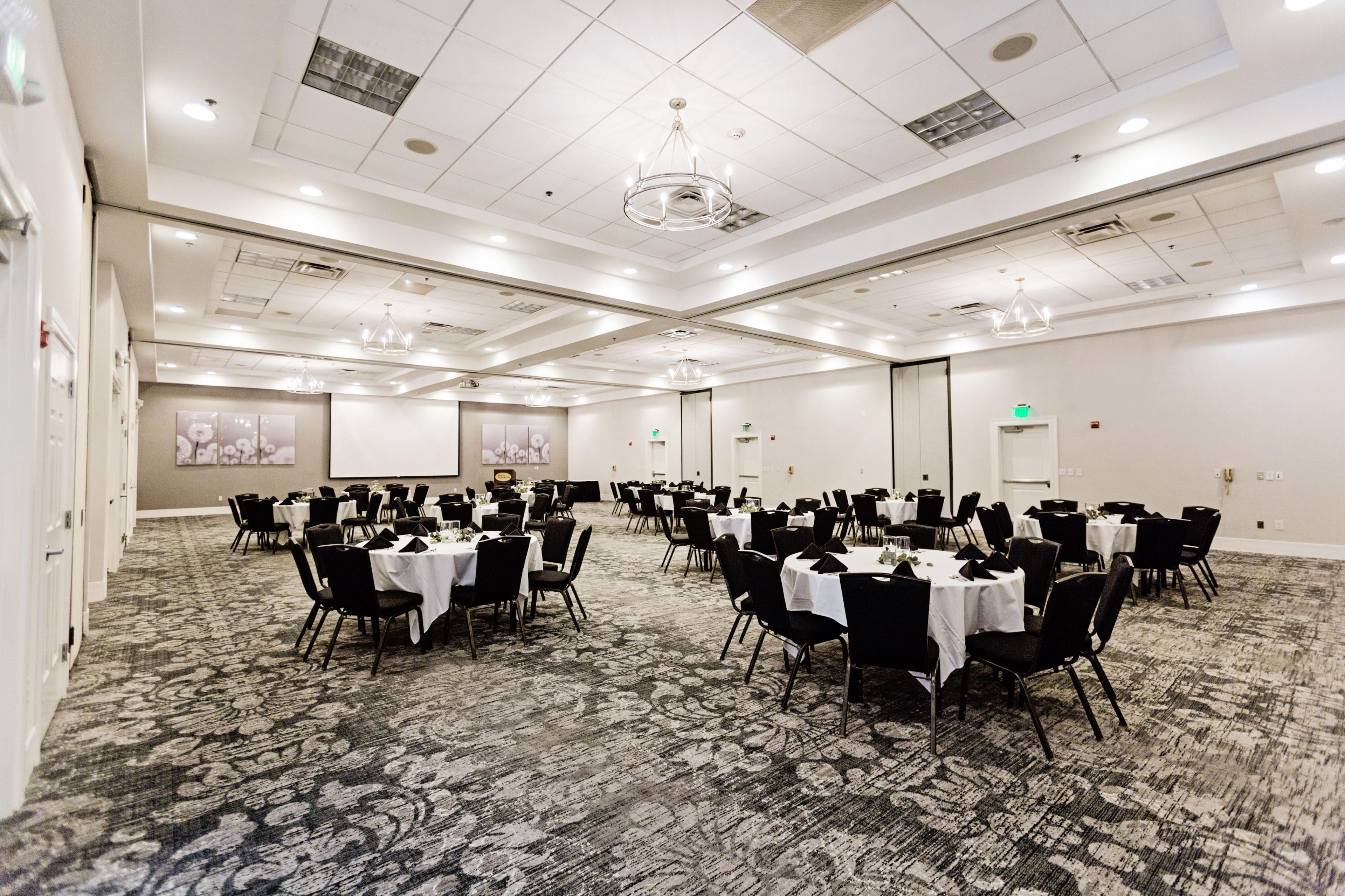 A conference room with round tables, black chairs, and a carpeted floor.