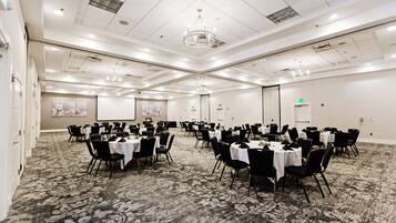 A conference room with round tables, black chairs, and a carpeted floor.