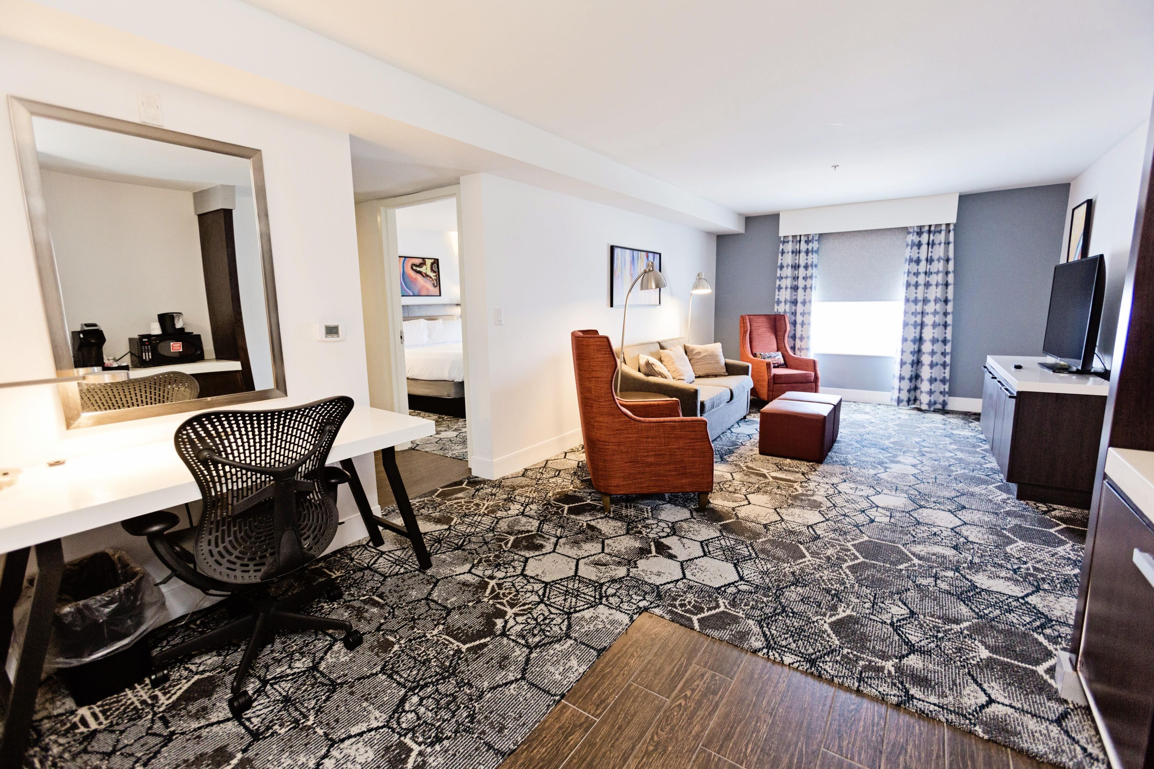 Une chambre d’hôtel équipée d’un bureau, d’une chaise, d’un canapé et d’une télévision.