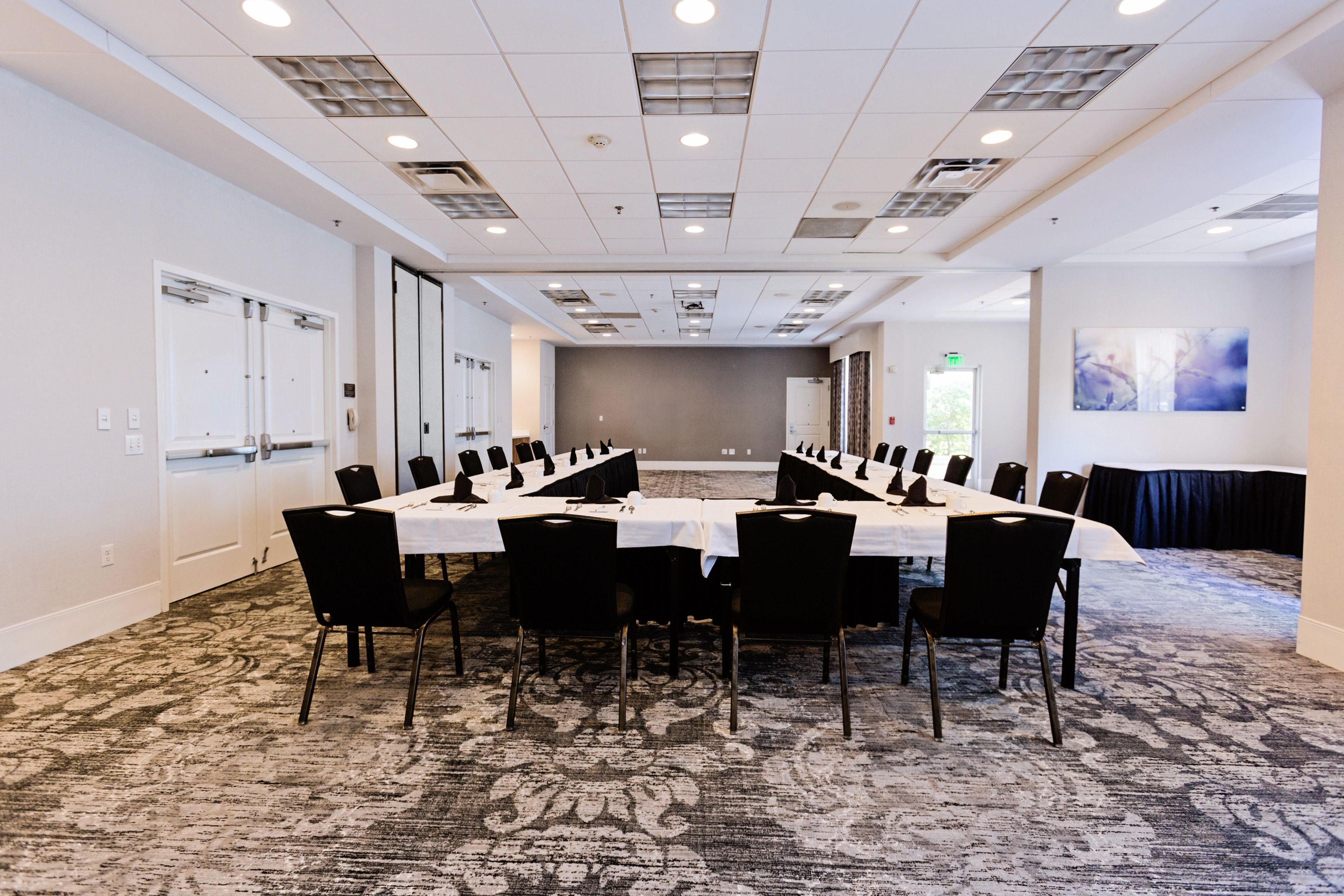Una sala conferenze con un lungo tavolo, sedie e pavimento rivestito di moquette.
