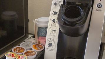 Una cafetera Keurig con un recipiente para gotas, un soporte para cápsulas de café y una taza de café.
