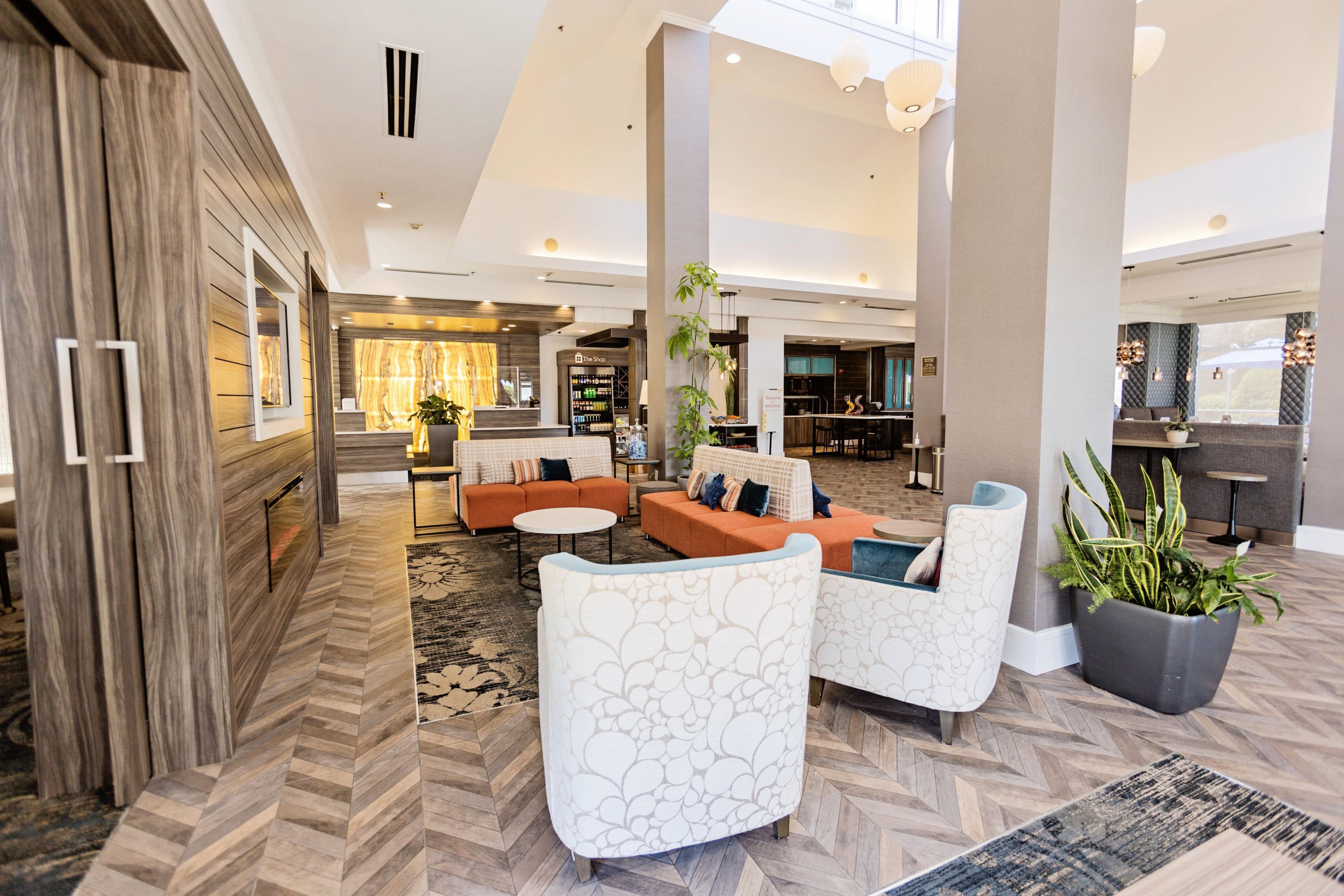 Un hall d’entrée spacieux, doté d’un sol en parquet disposé en point de Hongrie, d’un comptoir d’accueil et d’un espace détente avec des canapés et des fauteuils modernes.