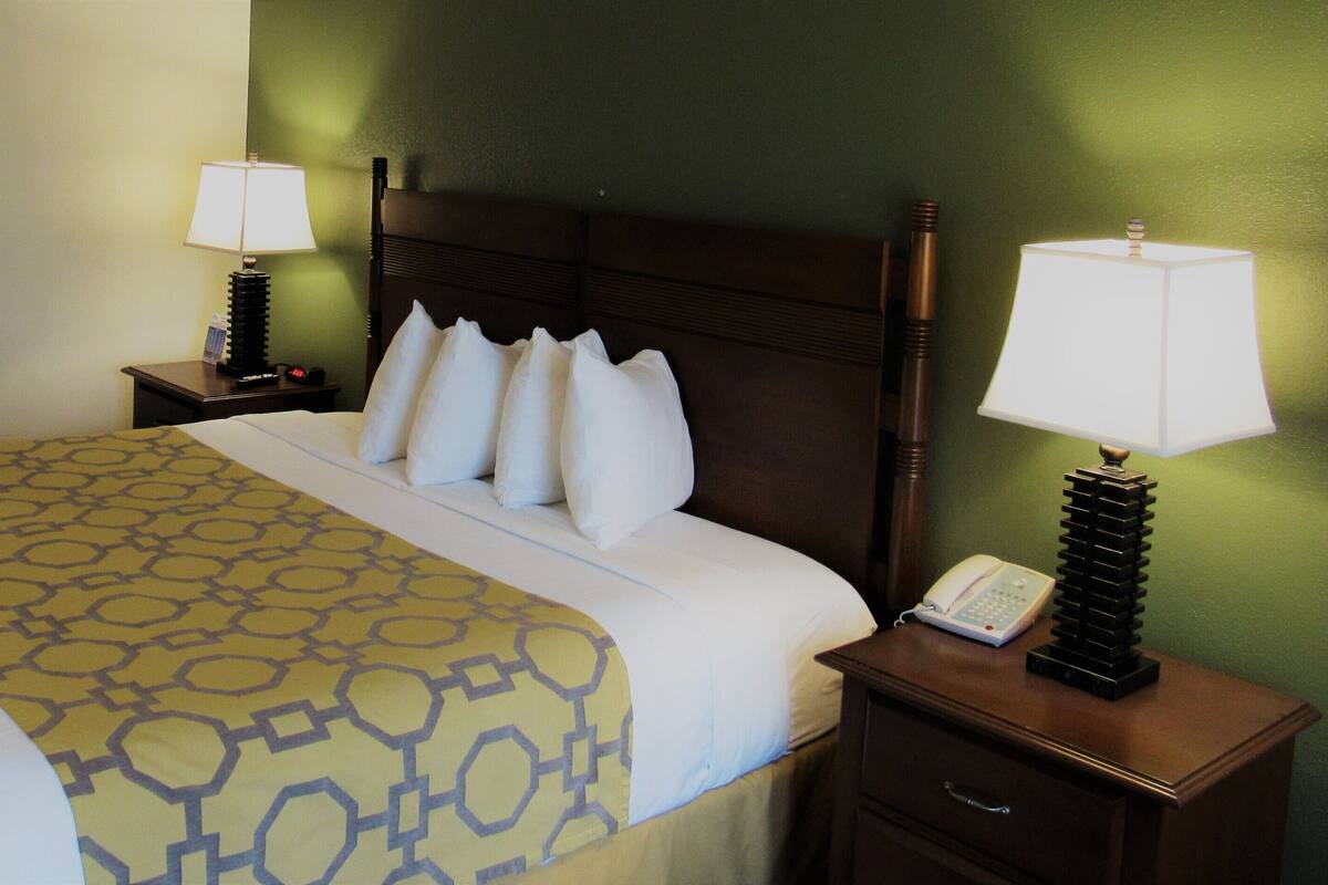A hotel room with a large bed, two bedside tables, a telephone, and a lamp on each table.