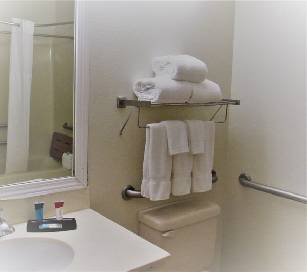 A bathroom with a white sink, a mirror, a toilet, and a towel rack with folded towels.
