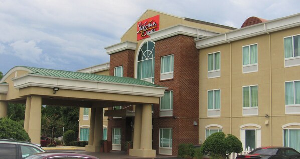 A hotel with a brick facade, a covered entrance, and a sign for 'Skyline Suites'.