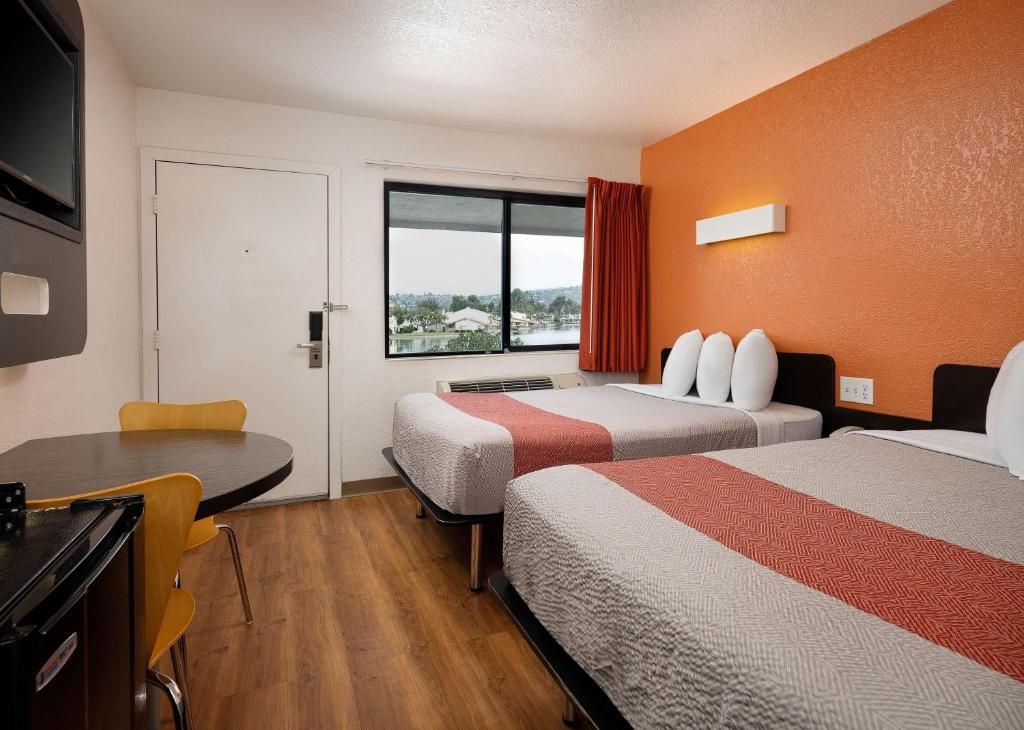 A hotel room with two beds, a desk, and a chair.