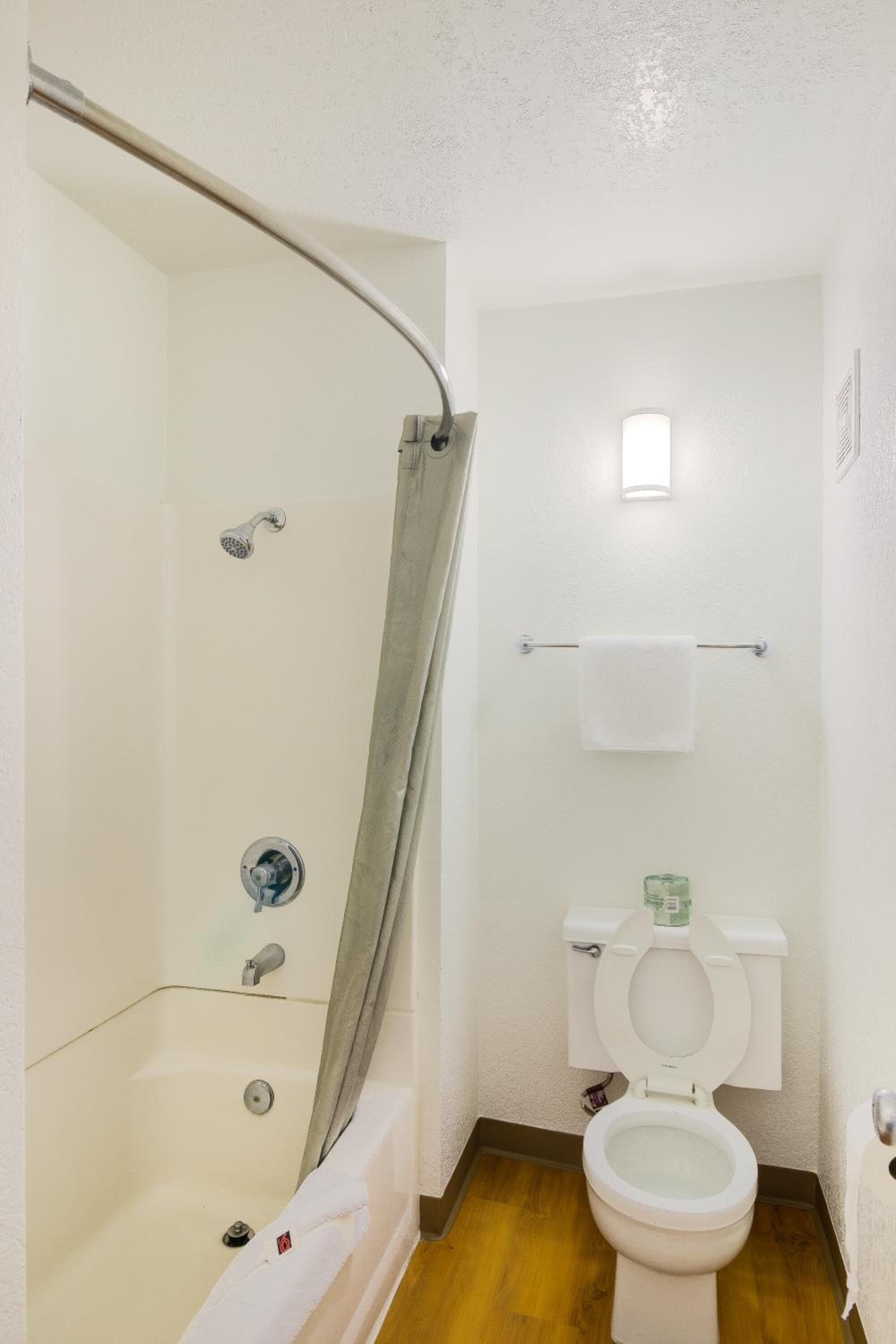 Une petite salle de bain propre, équipée d’une douche, de toilettes et d’un porte-serviettes.