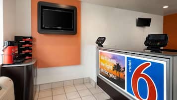 A reception area with a digital display, a television, and a counter with a sign.