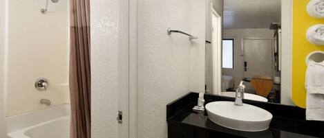 A bathroom with a bathtub, a sink, and a mirror.