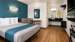 A hotel room with a bed, a small table, a chair, a desk, a mirror, and a TV. - Vagabond Inn Camarillo (Camarillo)
