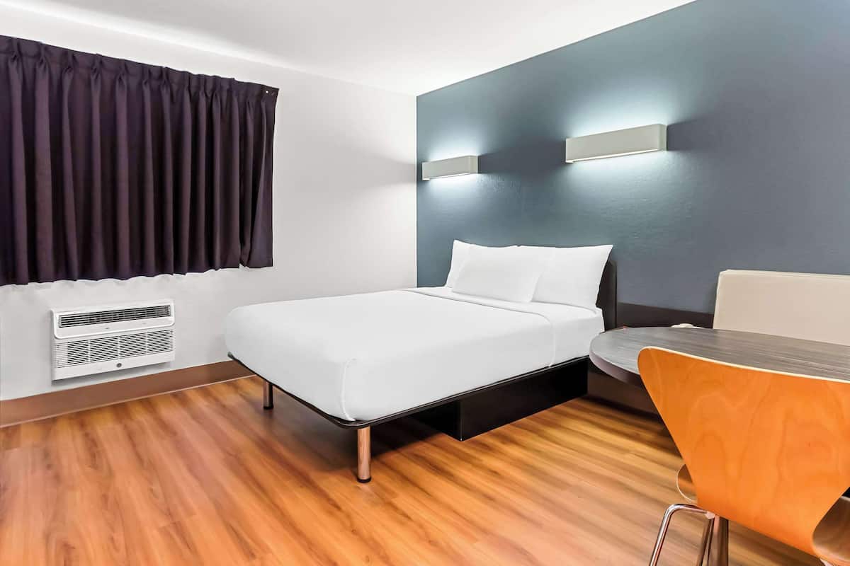 A modern hotel room with a bed, a desk, and a chair.