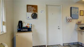 A small room with a coffee station, a door, and a wall-mounted sign.
