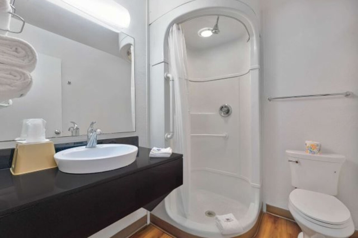 A modern bathroom with a white sink, a mirror, a shower enclosure, and a toilet.