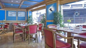 Un restaurante con mesas de madera, sillas rojas, ventanas amplias y paredes azules.
