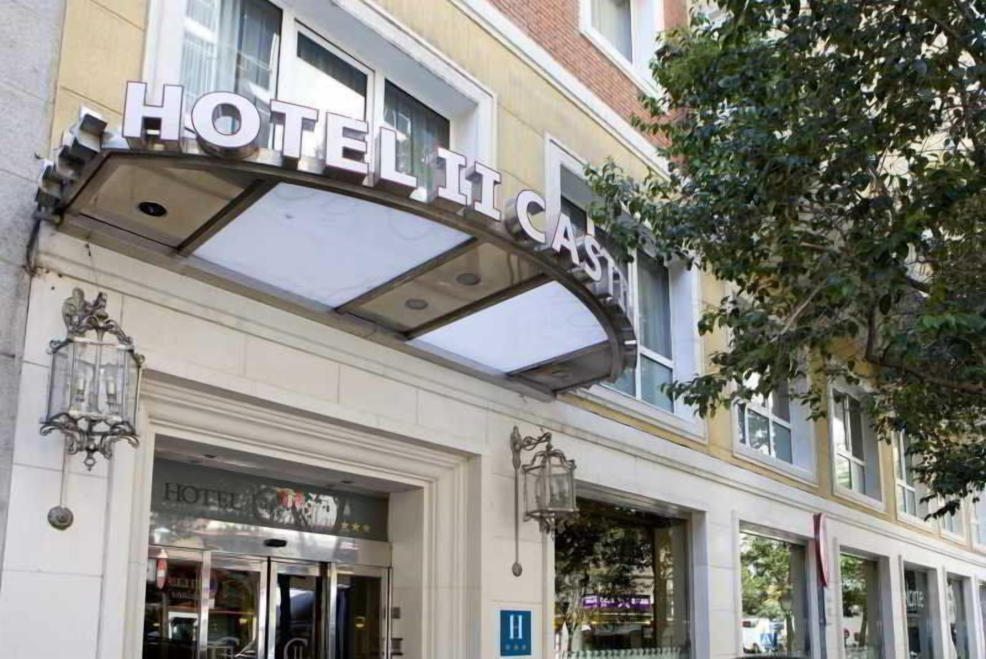 A hotel entrance with a prominent sign, a glass door, and a lamp post.
