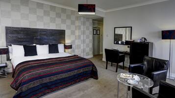 Habitación de hotel con una cama grande, un escritorio, una silla y una pequeña mesa con cosas para el desayuno.