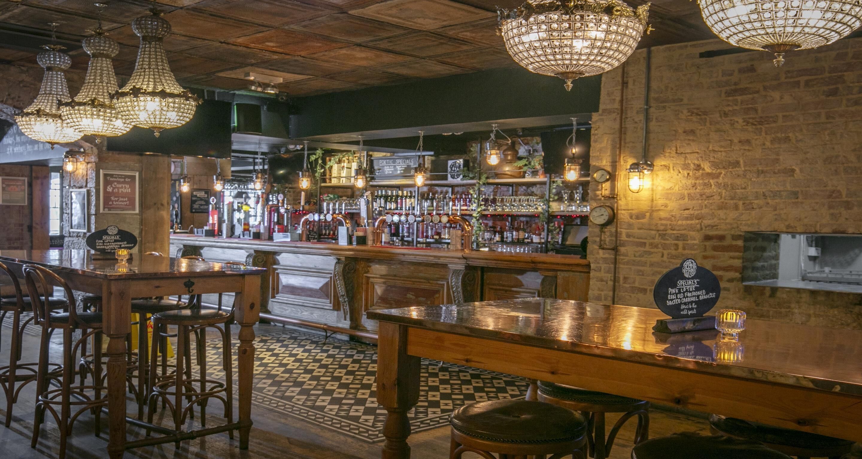 A bar area with wooden furniture, a checkered floor, and hanging crystal chandeliers.
