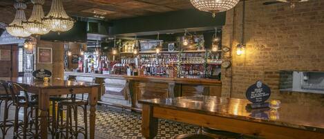 A bar area with wooden furniture, a checkered floor, and hanging crystal chandeliers.