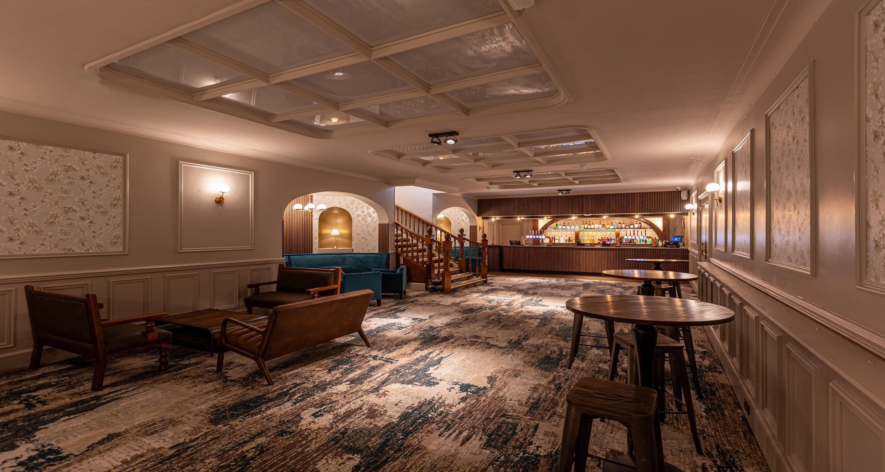 A hotel lobby with a bar, seating area, and a staircase.