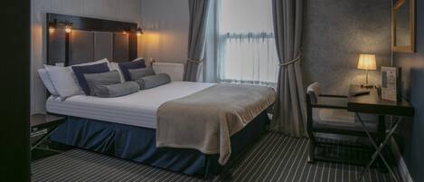 Een verzorgde hotelkamer met een bed, nachtkastje, lamp en uitzicht op het landschap.