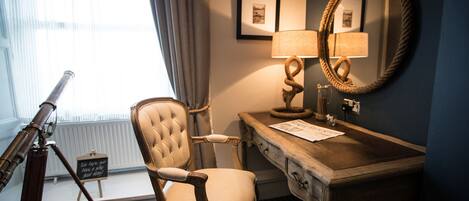 A room with a desk, chair, lamp, mirror, and a telescope.