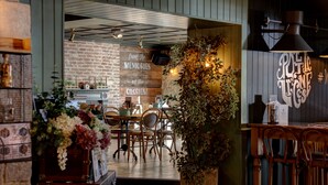 A restaurant interior with a brick wall, wooden furniture, and a large potted plant. - The Roker Hotel, BW Premier Collection (Sunderland)