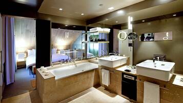 A modern bathroom with a large bathtub, two sinks, and a mirror with a round mirror above.
