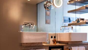 Un baño moderno con dos lavamanos, un espejo grande y un perchero para toallas.