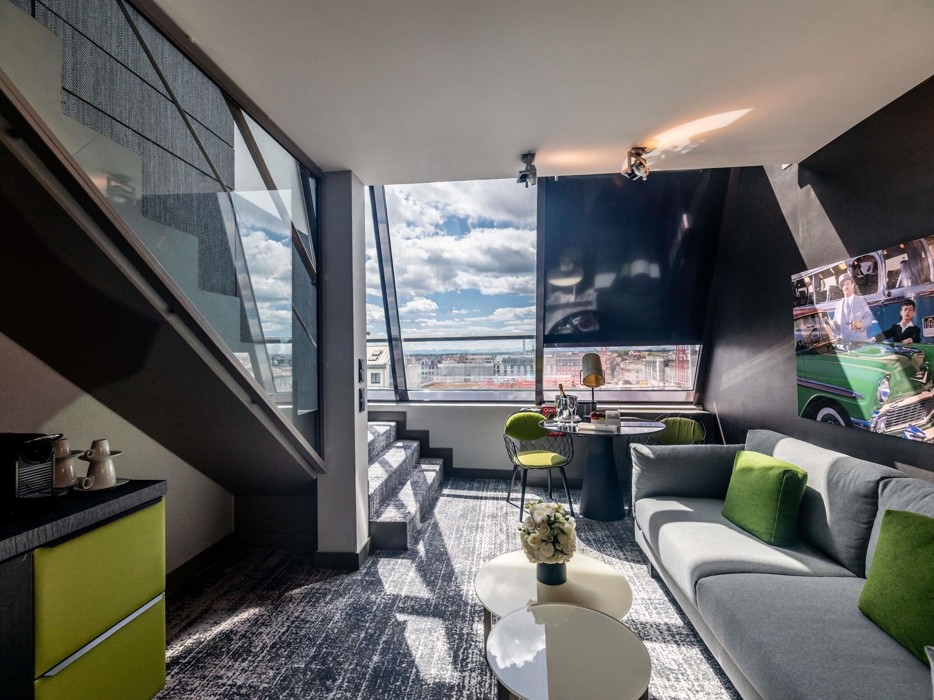 Un salon moderne avec un canapé, une table basse et une vue sur la ville grâce à de grandes fenêtres.