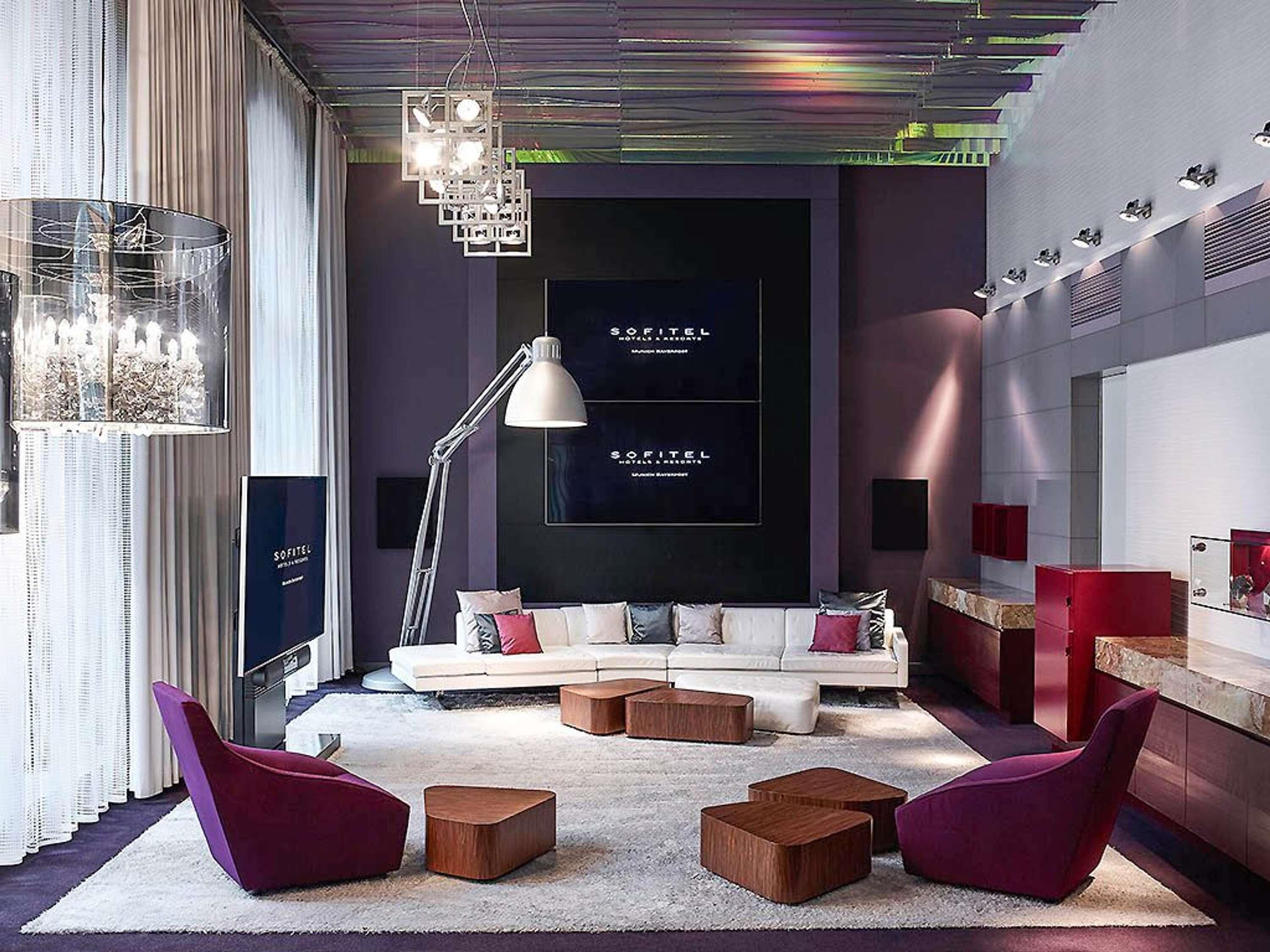 Una sala de estar moderna con un sofá, dos sillones, una lámpara de pie y un candelabro.