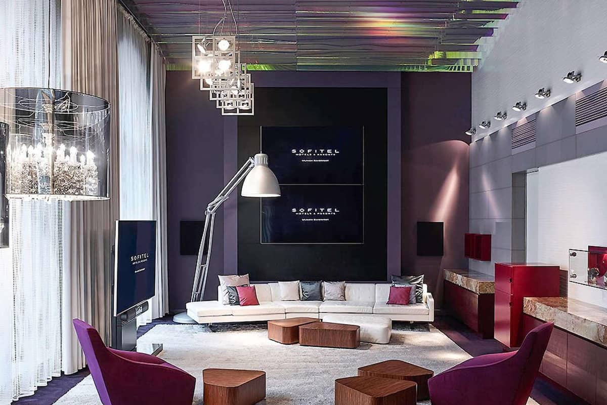 A modern living room with a sofa, two chairs, a floor lamp, and a chandelier.