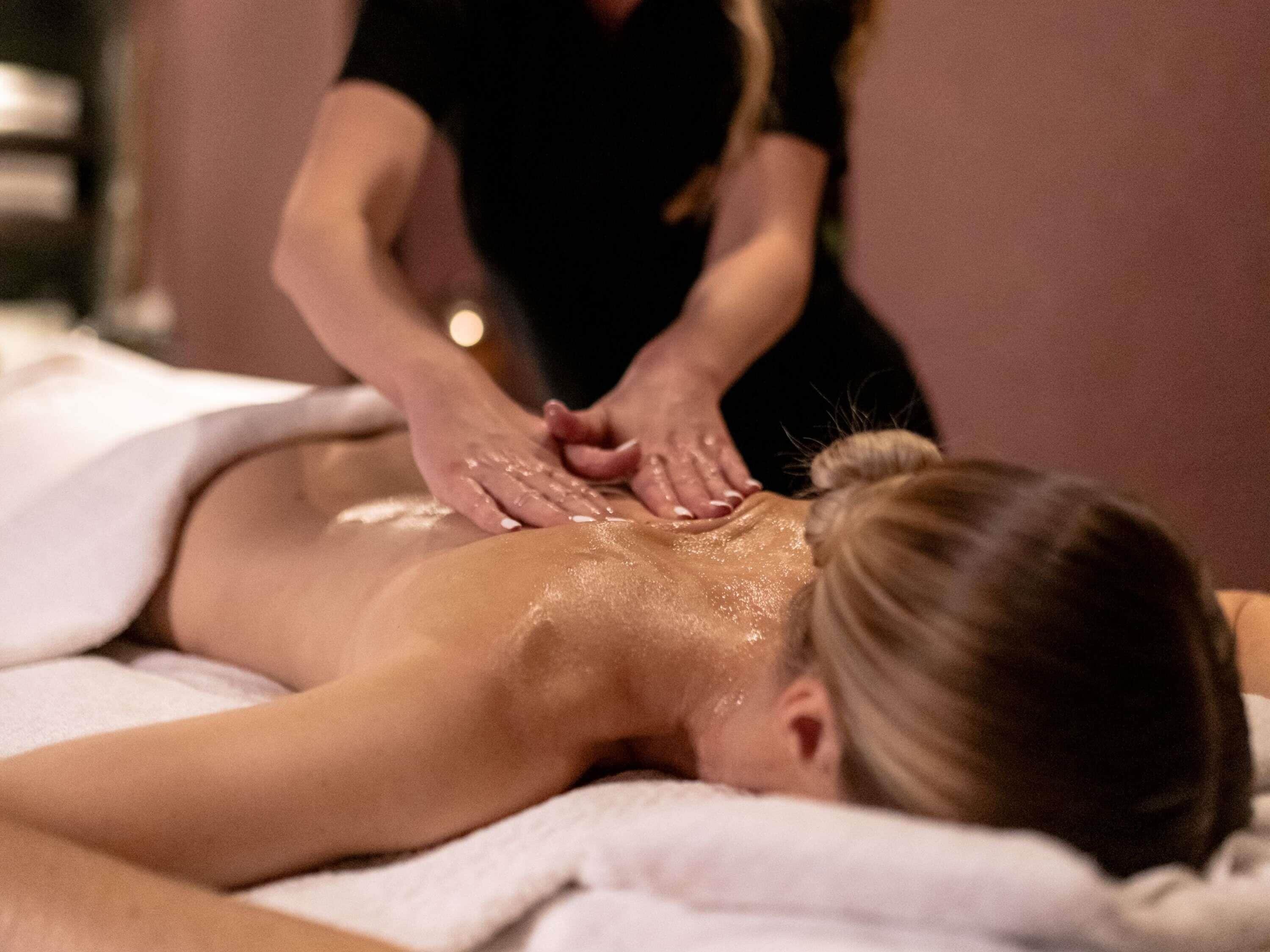 A person receiving a massage on a massage table with a towel covering the lower body.