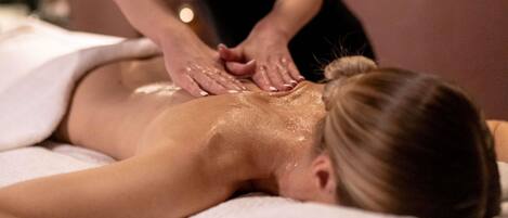 A person receiving a massage on a massage table with a towel covering the lower body.