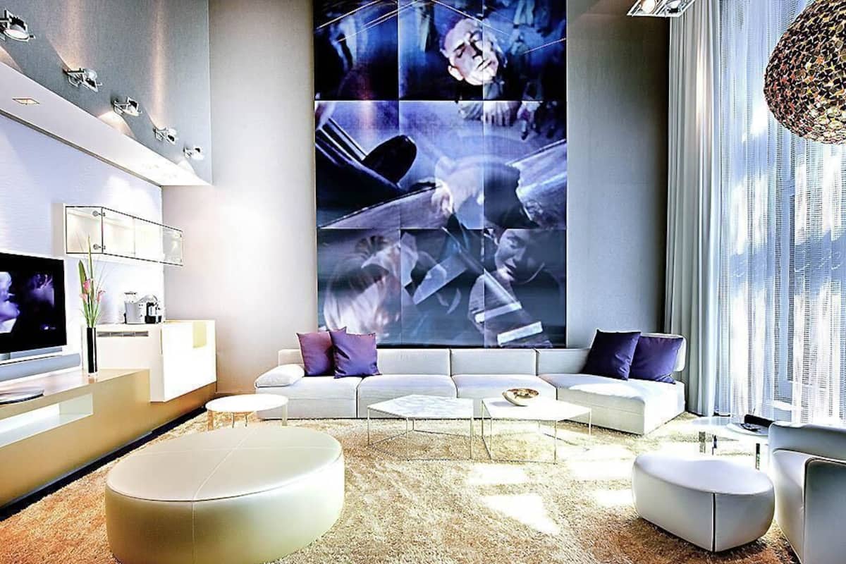 Een moderne woonkamer met een grote muurschildering, een zithoek, een flatscreen televisie en een salontafel.