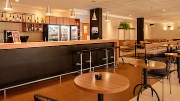Un área de bar moderna con barra, taburetes y distintos arreglos de asientos.