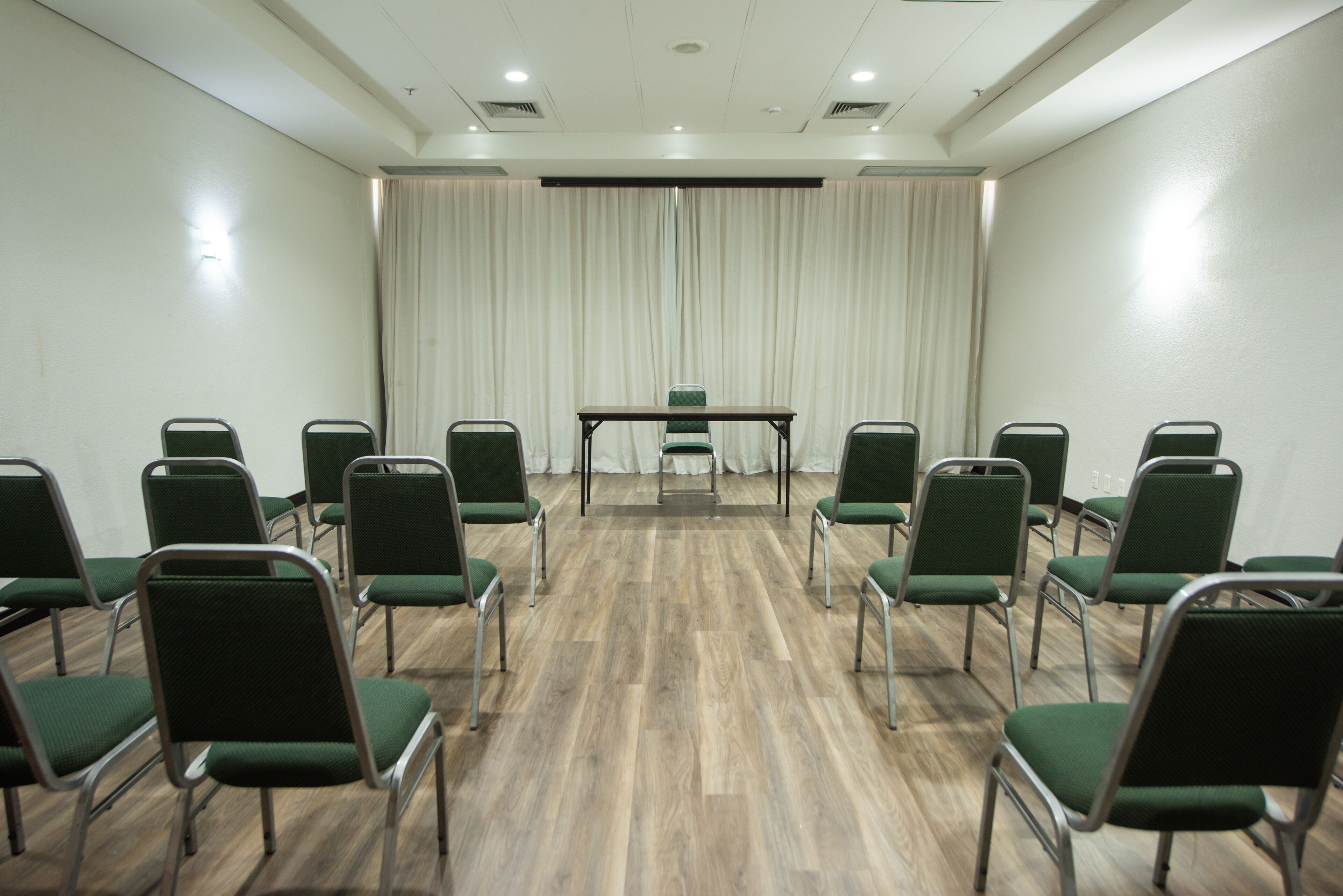 Un salón de conferencias con una larga mesa y varias sillas dispuestas en filas.