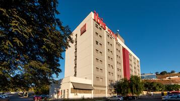 Un hotel alto de varios pisos con un letrero rojo destacado en la parte superior.