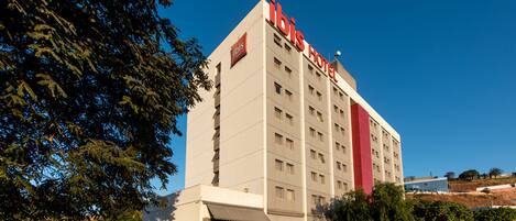Un hotel alto de varios pisos con un letrero rojo destacado en la parte superior.