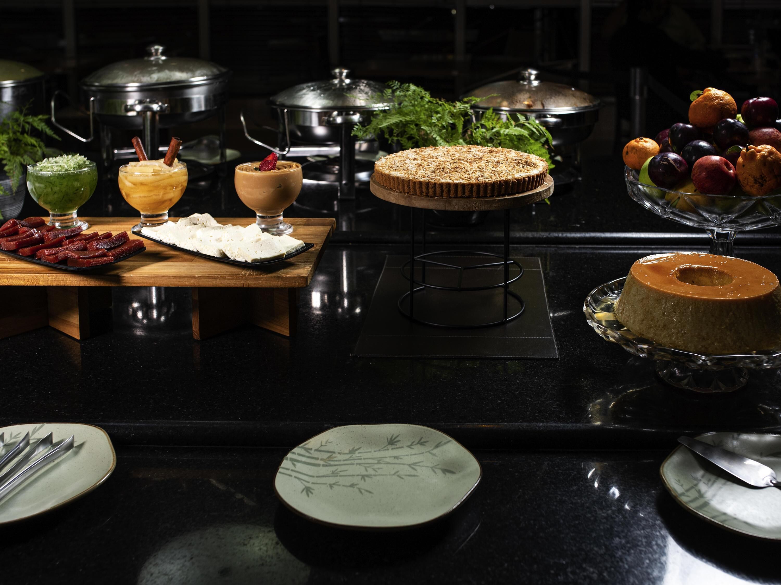 A buffet setup with various dishes, including a cake, fruit, and a dessert.
