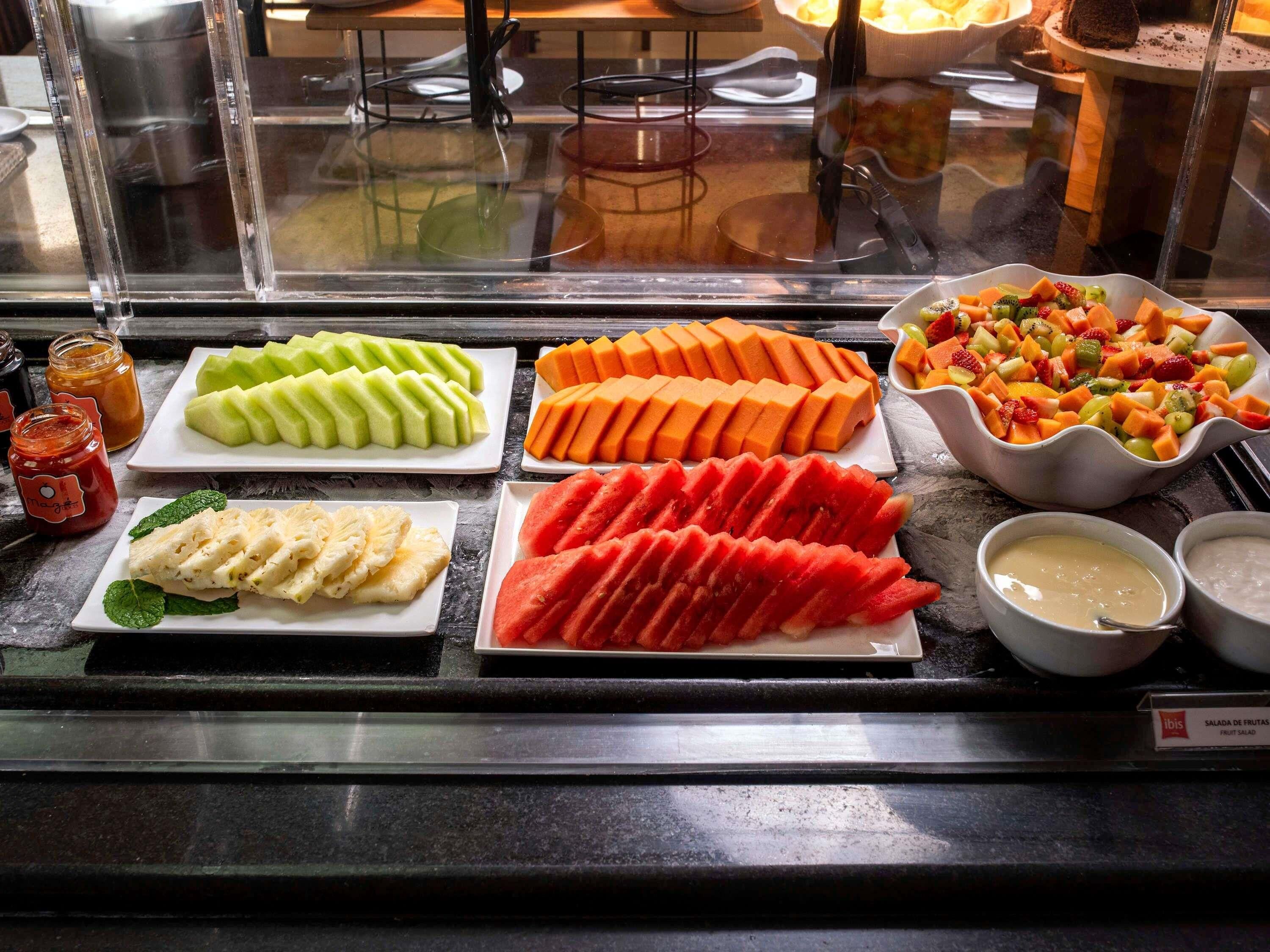 A fruit salad display with various fruits and condiments.